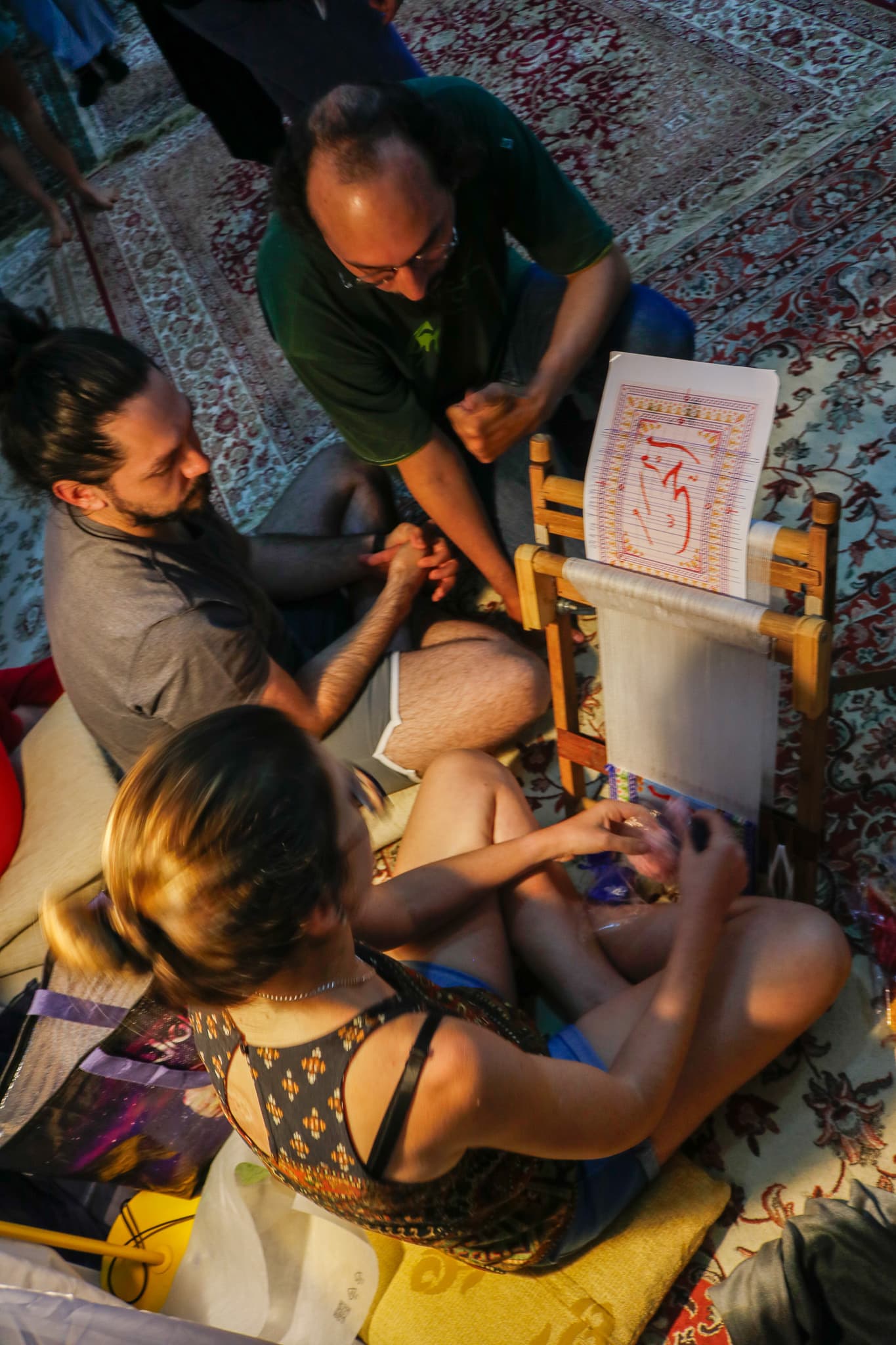 Três pessoas trabalhando no tear pequeno